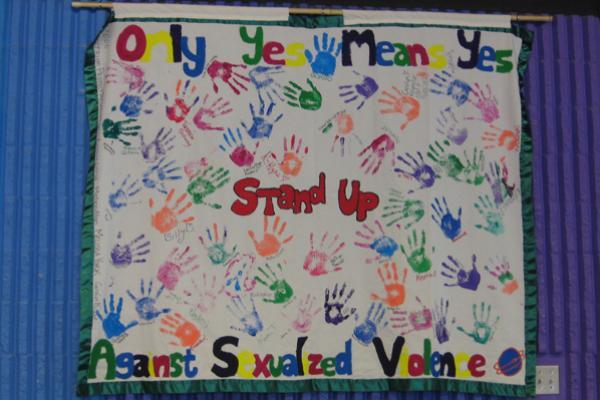 Hand prints covering a banner: "STand up"